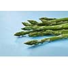Organic green asparagus in a bunch ready to cook healthy vegetarian food on blue background.