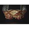 Men's hands hold organic dark bread on a dark background close-up