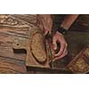 top view of fresh bread cut into a man's hands on a wooden board.in the background of a brown table flat lay