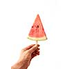 A man's hand holds a juicy piece of watermelon lolly on a white background with space for text. The concept of fruit ice cream