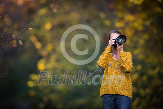 Pretty, female photographer taking pictures outdoor on a lovely autumn day - shallow DOF, color toned image