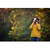 Pretty, female photographer taking pictures outdoor on a lovely autumn day - shallow DOF, color toned image