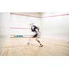 Squash player in action on a squash court (motion blurred image; color toned image)