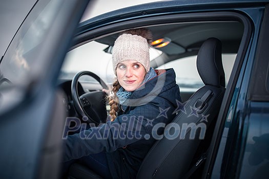 Woman driving a car - female driver at a wheel of a modern car, looking happy, smiling with a relaxed smile (shallow DOF; color toned image)