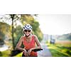 Pretty, young woman biking on a mountain bike enjoying healthy active lifestyle outdoors in summer (shallow DOF)