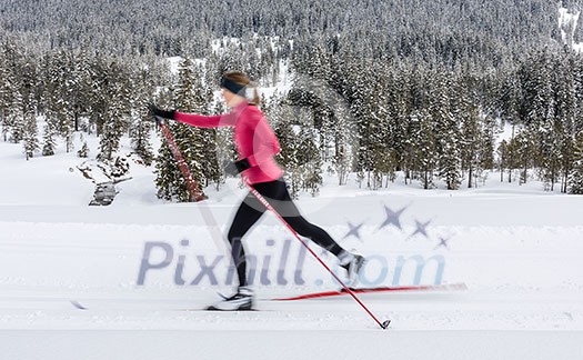 Cross-country skiing: young woman cross-country skiing on a winter day (motion blurred image)