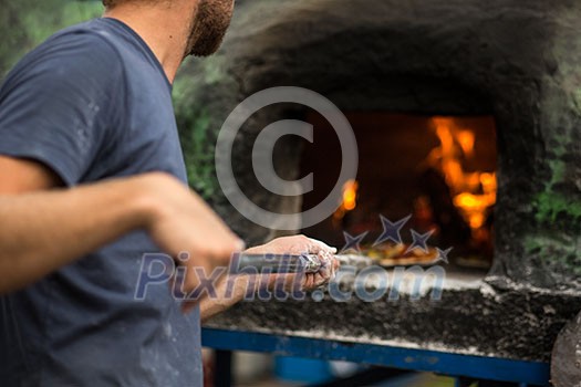 Cook baking pizza in a traditional stone wood fired oven Cook baking pizza in a traditional stone wood fired oven