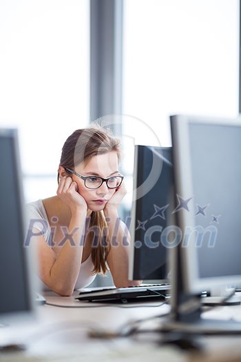 Pretty, female student looking at a desktop computer screen, learning unpleasant news about her exam results. University/office/school concept Pretty, female student looking at a desktop computer screen, learning unpleasant news about her exam results. University/office/school concept