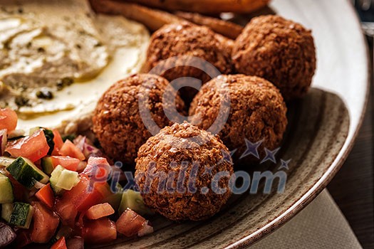 Close-up of Traditional falafel balls with salad and hummus on a plate.