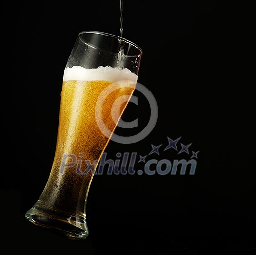 Pouring beer into glass over black background