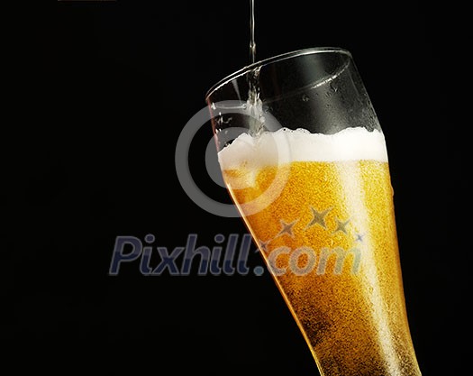 Pouring beer into glass over black background