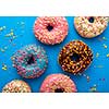 Variety of colorful tasty glazed donuts on a colored background.