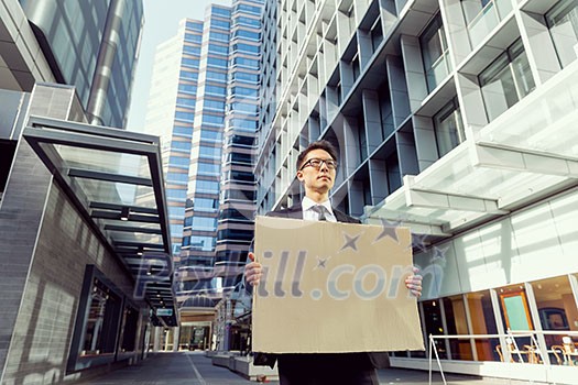 Businessman in a city street holding a blank banner Businessman in a city street holding a blank banner