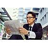 Businessman sitting outdoors with newspaper