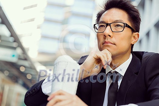 Businessman sitting outdoors with newspaper