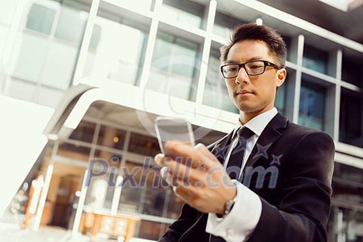 Businessman in city holding his mobile Businessman in city holding his mobile