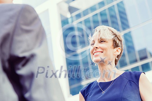 Businesswoman standing and talking to her colleague outdoors