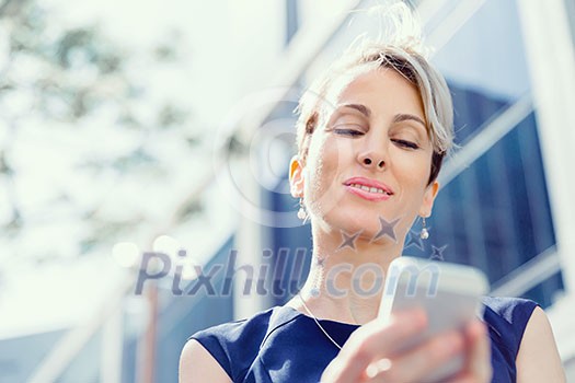 Businesswoman in city holding her mobile Businesswoman in city holding her mobile