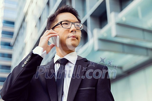 Businessman in city holding his mobile Businessman in city holding his mobile