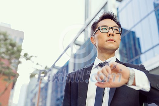 Businessman standing in street and looking at his watch Businessman standing in street and looking at his watch