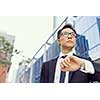 Businessman standing in street and looking at his watch