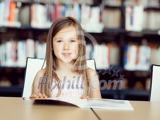 Little girl reading books in library