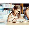 Little girl reading books in library