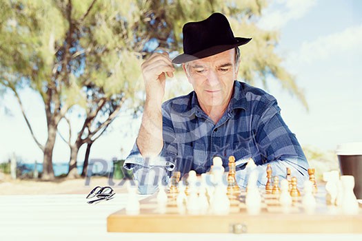 Elderly man sitting outdoors with chess Elderly man sitting outdoors with chess
