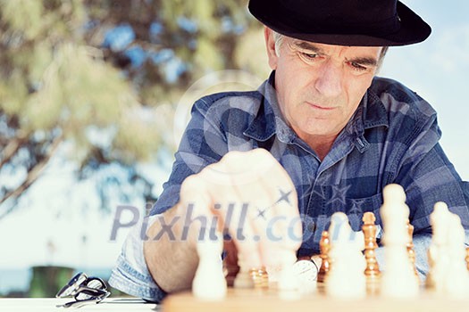 Elderly man sitting outdoors with chess Elderly man sitting outdoors with chess