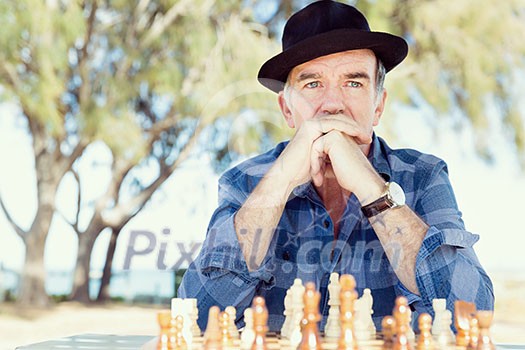 Elderly man sitting outdoors with chess Elderly man sitting outdoors with chess