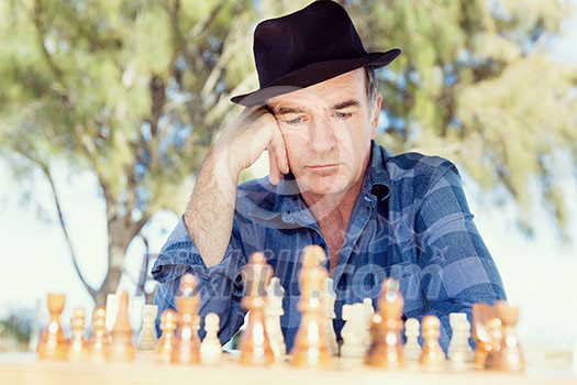 Elderly man sitting outdoors with chess Elderly man sitting outdoors with chess