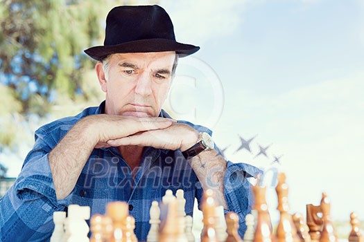 Elderly man sitting outdoors with chess Elderly man sitting outdoors with chess
