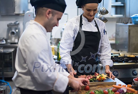 Professional team cooks and chefs preparing meal at busy hotel or restaurant  kitchen