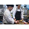 Professional team cooks and chefs preparing meal at busy hotel or restaurant  kitchen