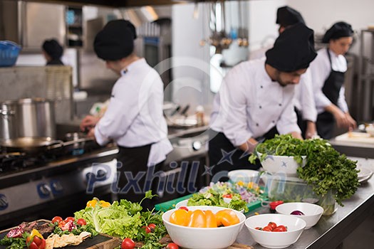 Professional team cooks and chefs preparing meals at busy hotel or restaurant  kitchen