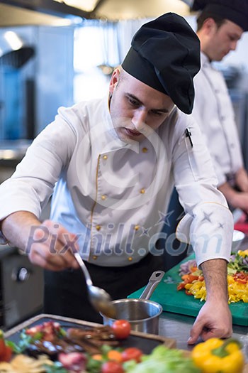 Chef finishing steak meat plate with Finally dish dressing and almost ready to serve at the table Chef finishing steak meat plate with Finally dish dressing and almost ready to serve at the table