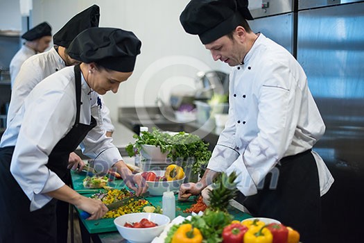 Professional team cooks and chefs preparing meals at busy hotel or restaurant  kitchen