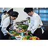 Professional team cooks and chefs preparing meals at busy hotel or restaurant  kitchen