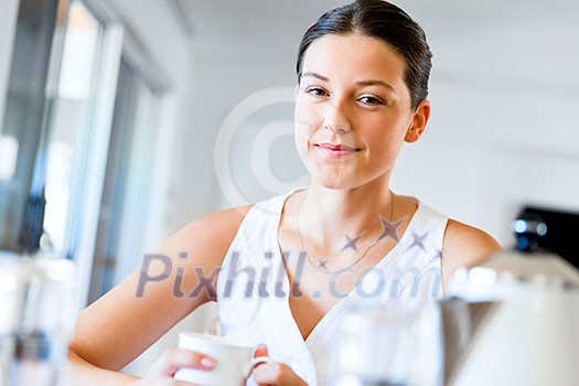 Attractive young woman with cup of tea or coffee at home