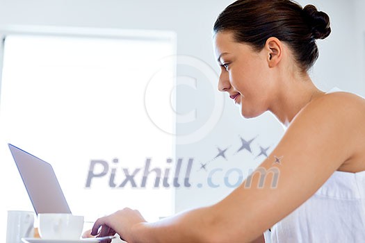 Young beautiful woman sitting at the table and working on her laptop Young beautiful woman sitting at the table and working on her laptop