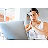 Young beautiful woman sitting at the table and working on her laptop