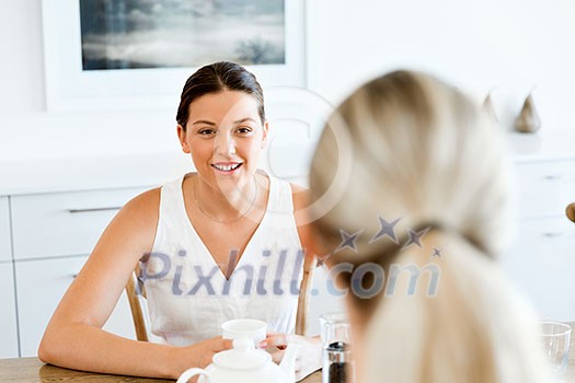 Young woman sitting at the kitchen table with her friend Young woman sitting at the kitchen table with her friend
