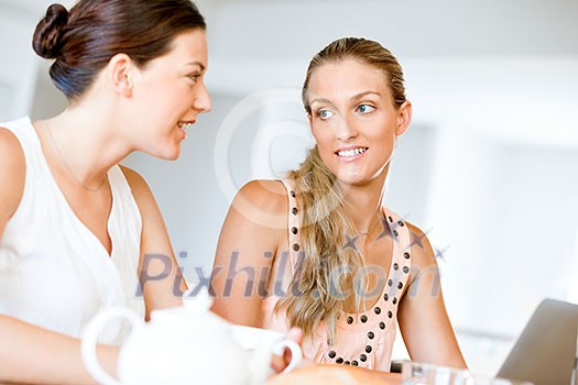 Two young women sitting and working together at laptop