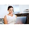 Young beautiful woman sitting on the sofa and working on her laptop