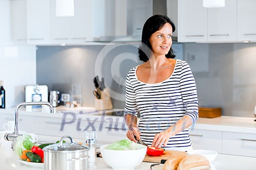 Image of beautiful woman standing in the kitchen and smiling
