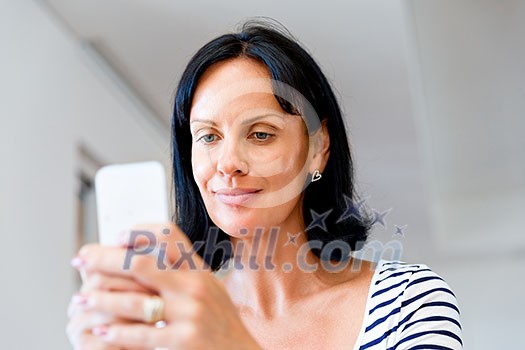 Portrait of attractive woman sitting at desk and holding mobile phone