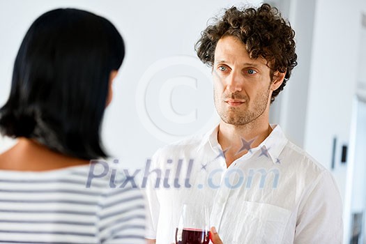 Young man holding a glass of wine and listening to woman