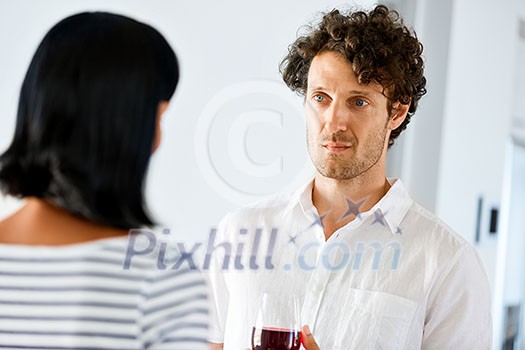 Young man holding a glass of wine and listening to woman Young man holding a glass of wine and listening to woman