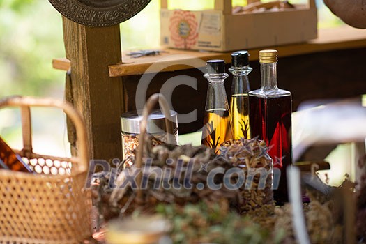 tincture or potion bottle in hand of herbalist  bunch of dry healthy herbs in background alternative medicine