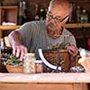 senior man gardener herbalist picking gathering fresh herbs for alternative medicine tea and poutting on balance